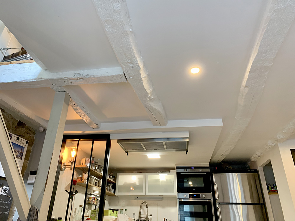 Faux-plafond isolé entre anciennes poutres et peinture