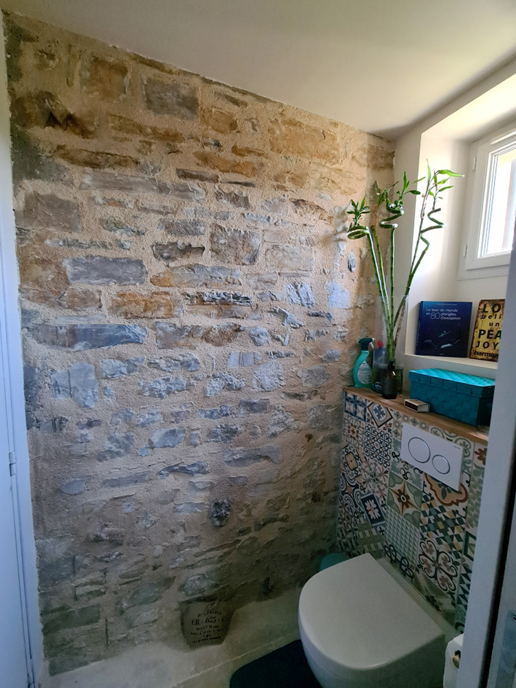 Réalisation des joints à la chaux sur un mur en pierres dans une salle de bain