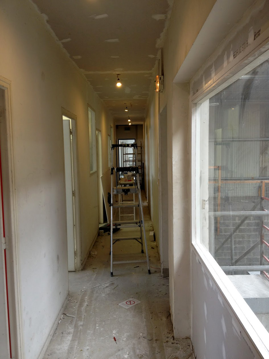 Faux-plafond acoustique dans un couloir d'accès avec éclairage